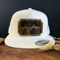 White snapback hat with scalloped dark cowhide patch and neon yellow-green hand-stitched border, branded with a registered cattle brand