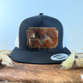 Black and white trucker snapback hat with mottled brown cowhide patch and olive green hand-stitched border, branded with a registered cattle brand
