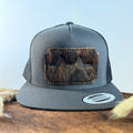 Charcoal grey snapback hat with near-black brindle cowhide patch and tonal dark stitched border, branded with a registered cattle brand