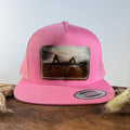 Pink trucker snapback hat with two-tone white and brown cowhide patch and cream tonal stitched border, branded with a registered cattle brand
